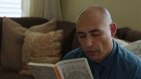 Man reading a book and having coffee at home Stock Footage 83188148