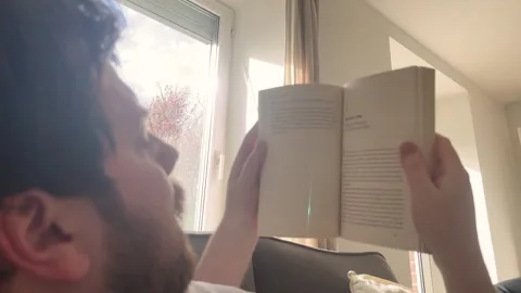Man reading a book and relaxing at home in natural light Stock Footage 334042254