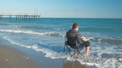 Man reading book on the beach Stock Footage 168298437