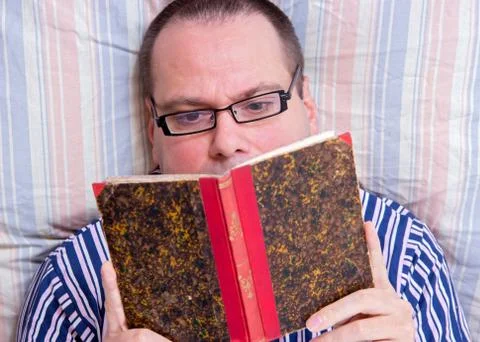 Man reading a book in bed Stock Photos