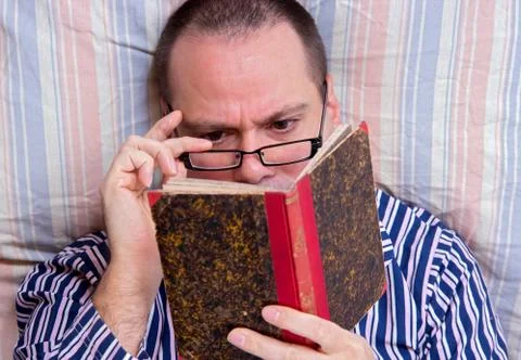Man reading a book in bed Stock Photos