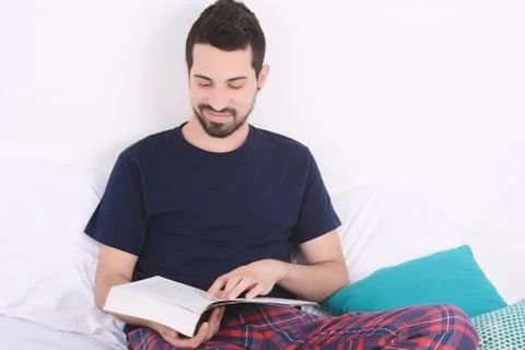 Man reading a book in bed. Stock Photos