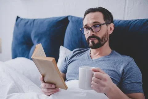 Man reading book in bed Stock Photos