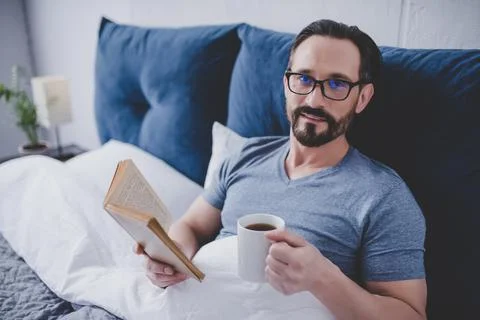 Man reading book in bed Stock Photos