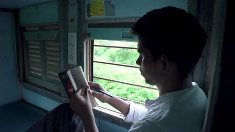Man Reading a Book Beside Window on Moving Train Stock Footage 345829438