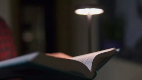 Man reading book close up, blurry background, warm cozy light Stock Footage 318966053