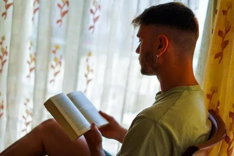 Man reading a book close to the window Stock Photos
