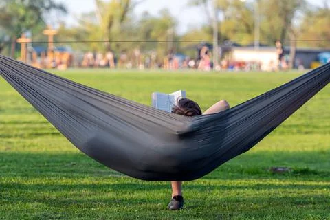Man reading book in comfortable hammock at green garden, viev from behind Stock Photos