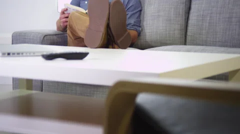 Man reading a book on the couch Stock Footage 67360582