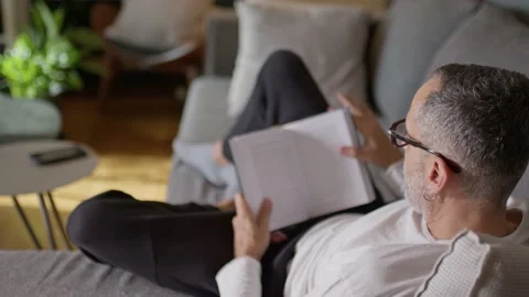 Man reading book on couch. Stock Footage 220441276