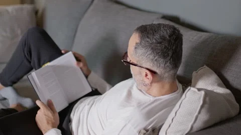 Man reading book on couch. Video stock 220464724