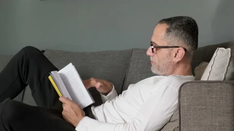 Man reading book on couch. Stock Footage 221168929