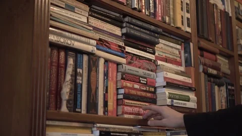 Man reading book in front of bookshelf looking and searching Stock Footage 73350494