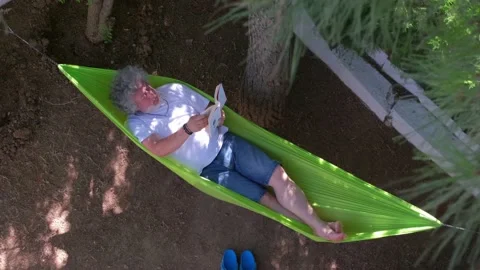 Man reading book on a hammock. 4K Stock Footage 195646417