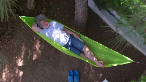 Man reading book on a hammock. 4K Stock Footage 195646676