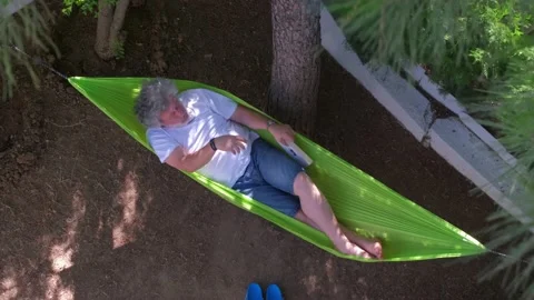 Man reading book on a hammock. 4K Stock Footage 195656246