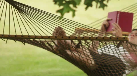 Man reading a book in a hammock Stock Footage 24701543