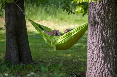 Man reading a book in a hammock. Stock Photos