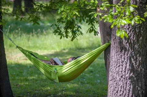 Man reading a book in a hammock. Stock Photos
