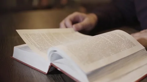Man reading book hand flips through page novel closeup. Male arm student book 4K Stock Footage 130936111