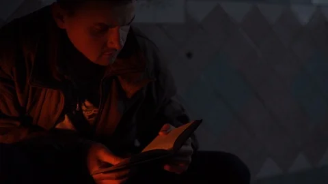 A man is reading a book, he has glare on his face Stock Footage 114630960