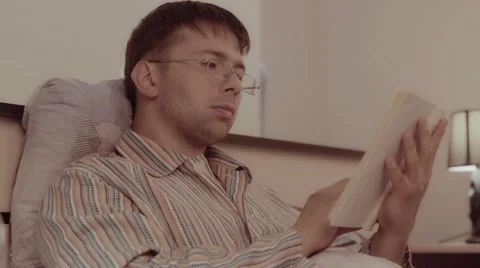 Man reading a book at home sitting in his bed 库存影片 68420626