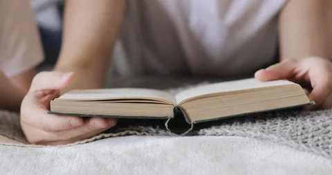 Man is reading a book laying in bed near another human, closeup view. Stock Footage 108018057