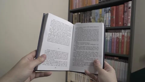 A man reading a book next to a bookshelf. Point of View Shot. POV video. Stock Footage 237942487