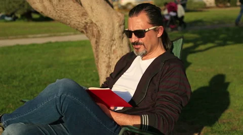 Man reading a book in the park Video stock 60824794