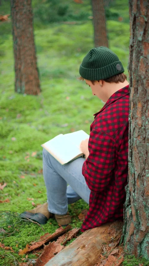 Man reading a book in a peaceful forest. Enjoying outdoor relaxation, nature the Vídeo Stock 345685380