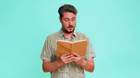 Man reading book with raised eyebrows showing surprise or interest in unexpected Stock Footage 347051689