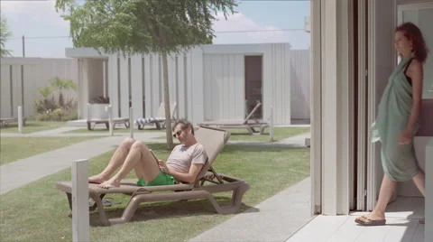 Man reading a book on a resort hammock Stock Footage 65219847