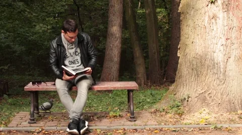 Man reading a book sitting on the bench Stock-Footage 68920698