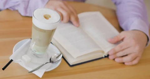 Man is reading a book sitting in cafe with cup of cappuccino. Stock Footage 106087190