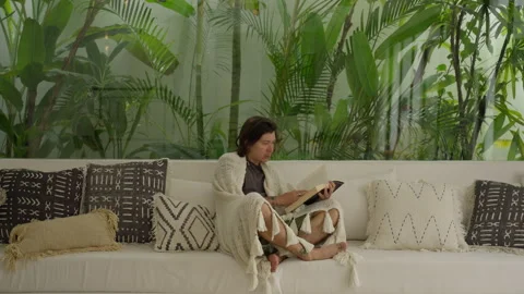 Man Reading Book Sitting On Couch. Male enjoys paper book reading resting alone Stock Footage 245463757