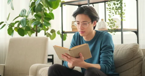 Man reading book on sofa Stock Footage 145292518