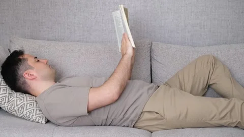 Man reading book on sofa Video stock 265428942