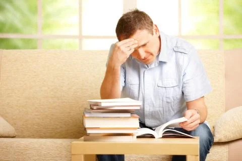 Man reading book on sofa Stock Photos