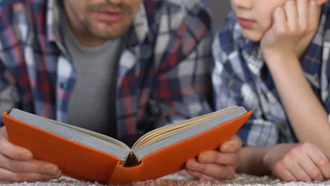 Man reading book son explaining school subject, help with homework, knowledge Video stock 87696159