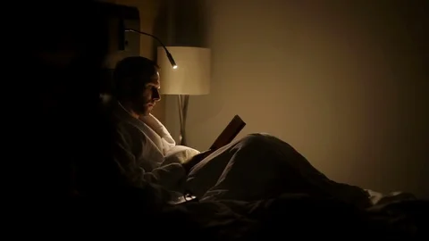 Man reading the book using the bed reading light in the late night Stock-Footage 82107857