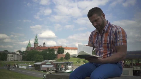 Man reading book on the wall by the river. 库存影片 52696279