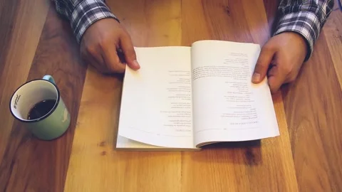 Man reading book while drinking coffee in cafe Stock Footage 246627889