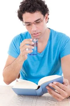 Man reading book while drinking healthy water from a glass Stock Photos