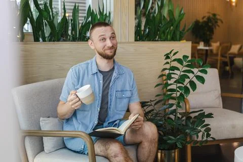 Man reading a book while enjoying coffee in a modern workspace for online e.. Stock Photos