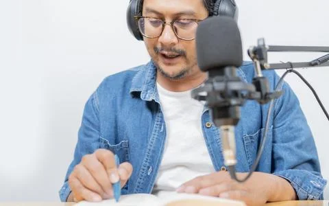 Man reading a book while recording a podcast or video in a studio with micr.. Stock Photos