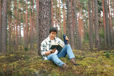 Man is reading a book while relaxing in a forest, enjoying a peaceful lifes.. Stock Photos