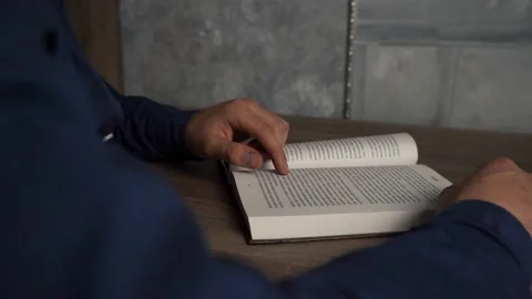 A man reading a book while sitting at a table Stock Footage 154473087