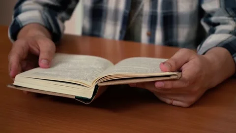 A man reading a book while sitting at a table 스톡 동영상 156727930