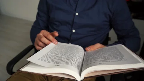 A man reading a book while sitting on a chair. Stock Footage 158841555
