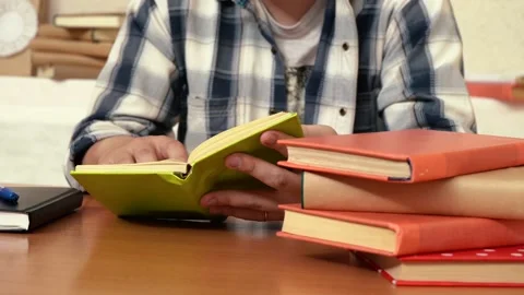 Man reading a book while sitting in the library at the table Stock Footage 160566145